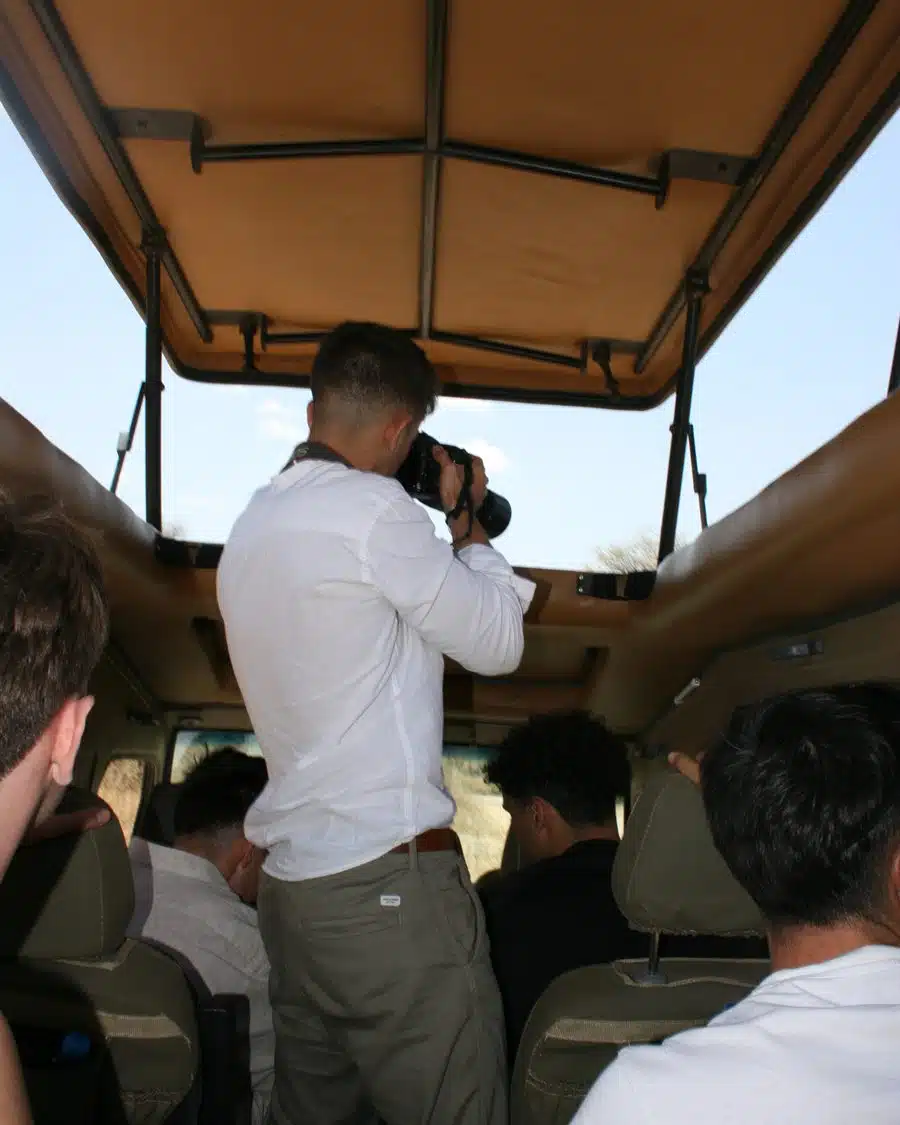 Gabriel, de espaldas, fotografiando desde un vehículo de safari