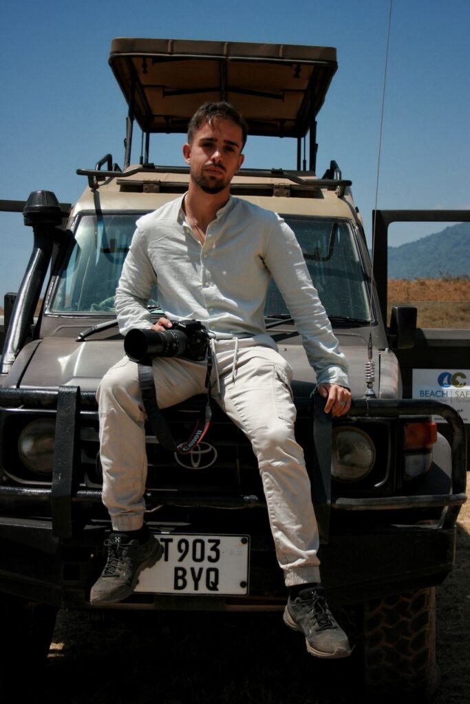 Gabriel Martínez sentado en el capó de un todoterreno de safari en Tanzania