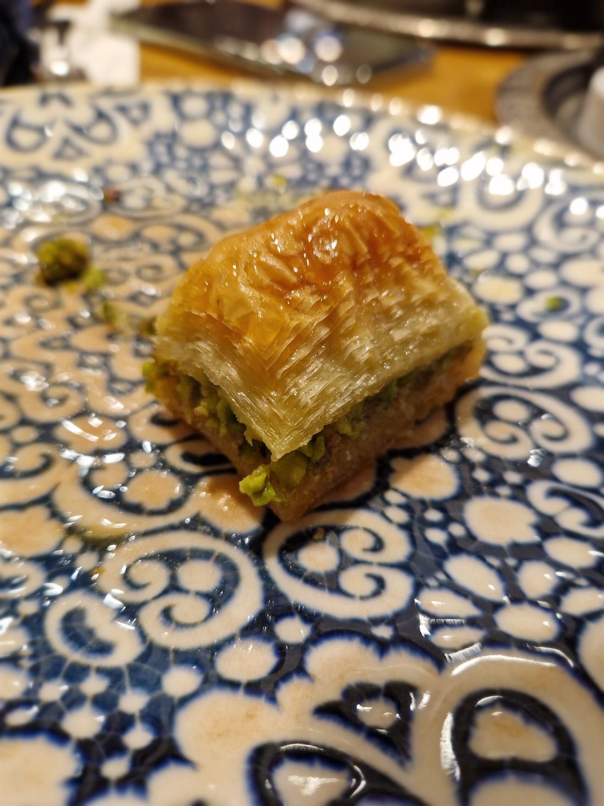 Pieza de baklava con pistacho sobre un plato decorado con motivos azules turcos