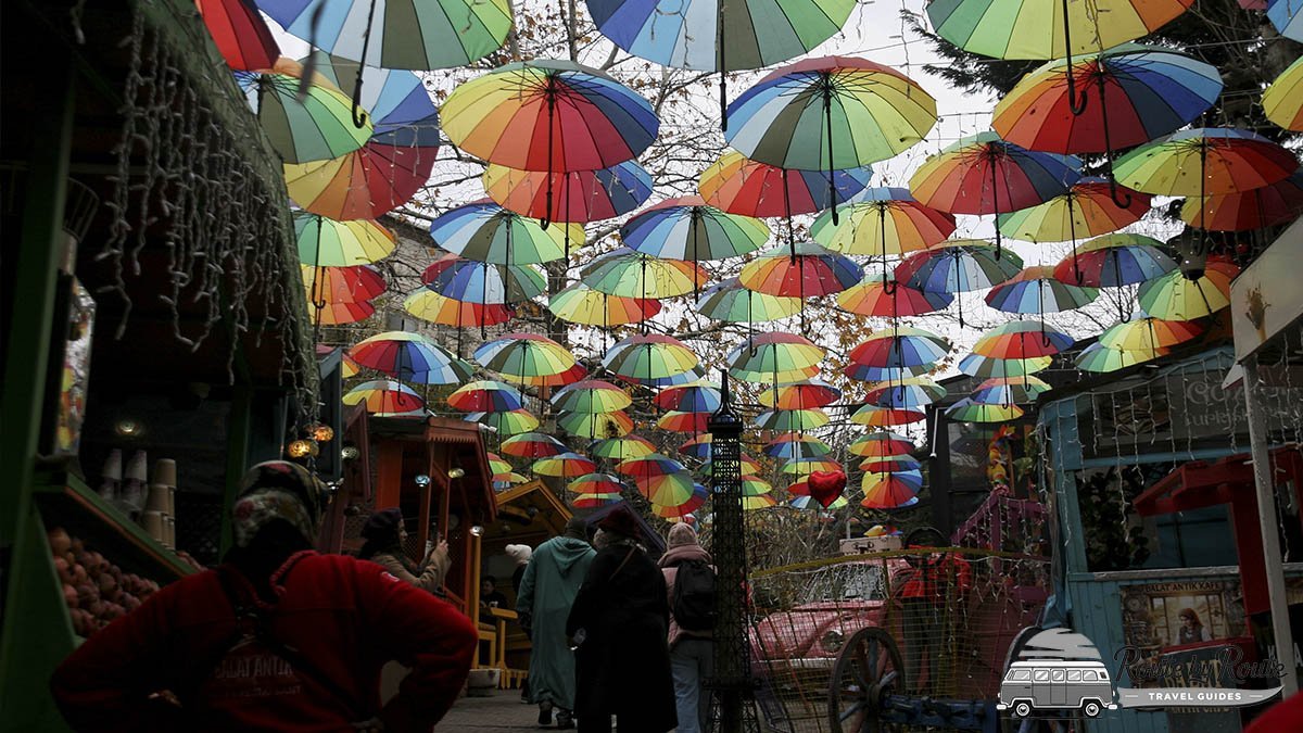 Calle de Balat cubierta de paraguas de colores, con puestos y cafés a los lados