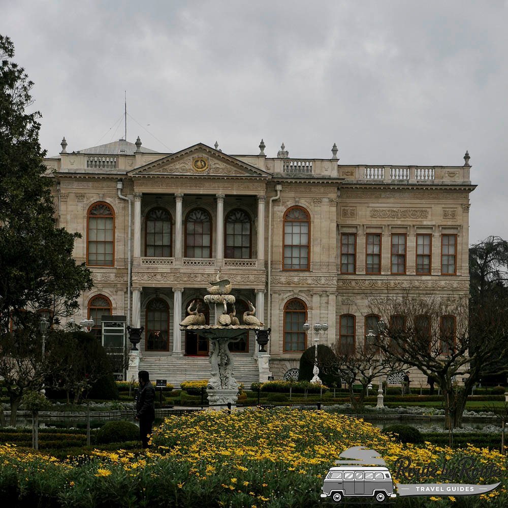 Fachada del Palacio de Dolmabahçe con una fuente y flores amarillas en los jardines
