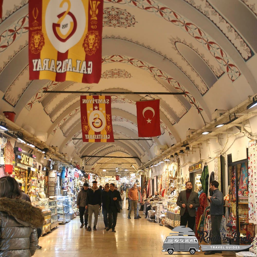 Pasillo cubierto del Gran Bazar de Estambul con tiendas de recuerdos y banderas turcas y del Galatasaray