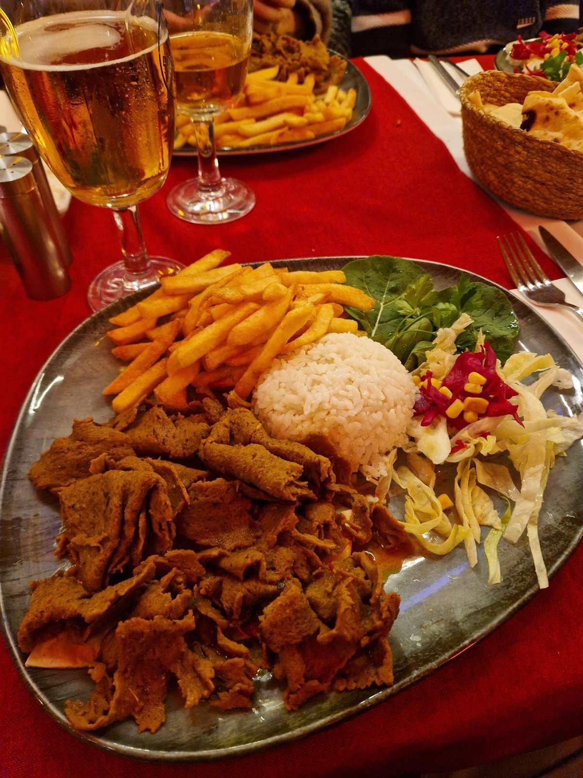 Plato de döner con arroz, patatas fritas y ensalada servido con una cerveza en un restaurante local de Estambul